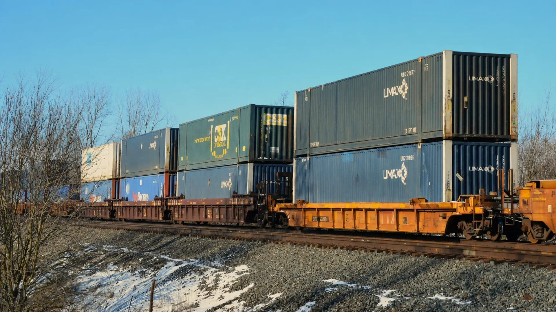 Double-stack intermodal containers moving by rail in a North American freight corridor.