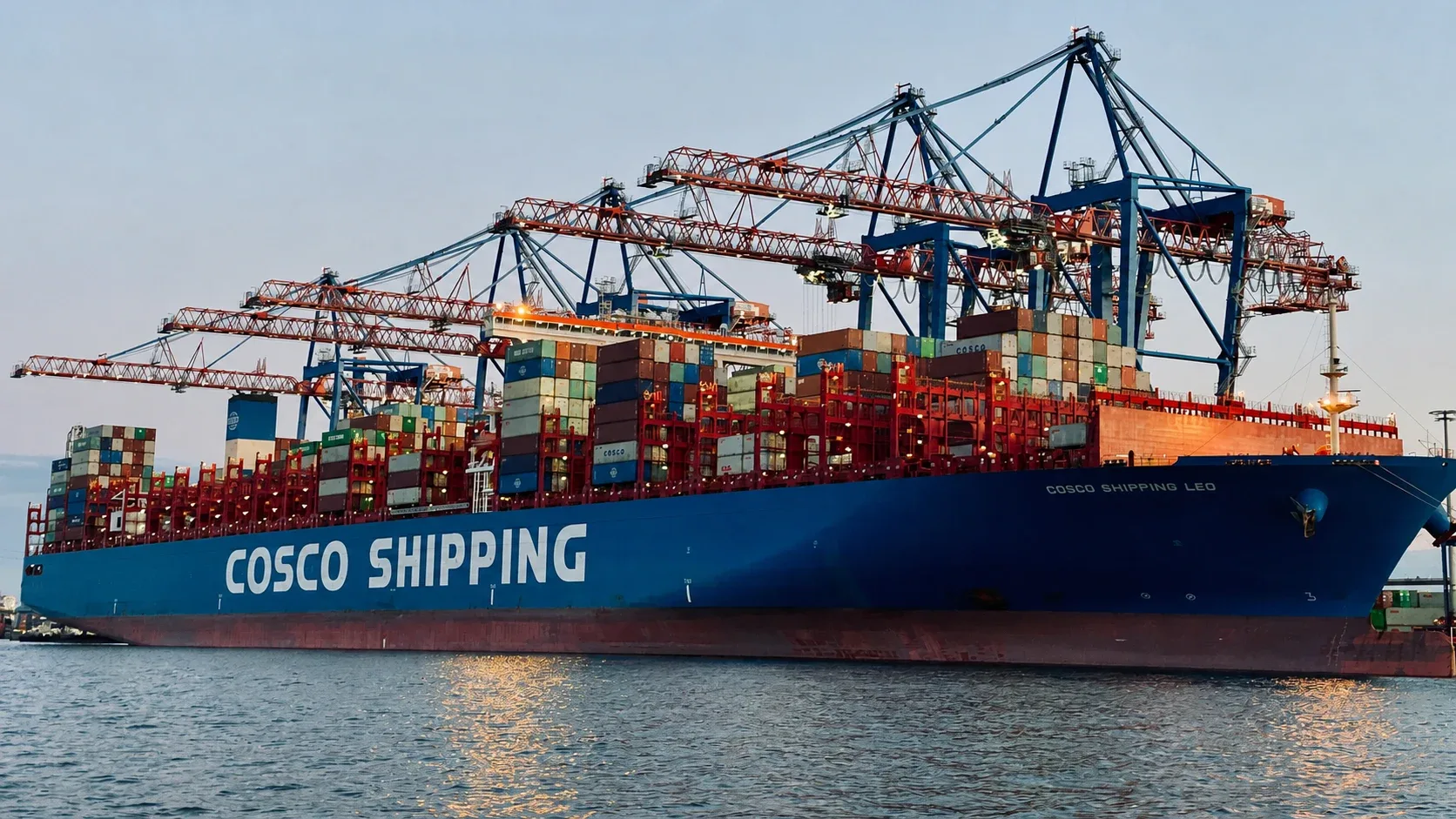 Container ship berthed beneath gantry cranes during terminal operations.